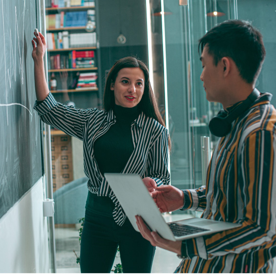two people discussing business while writing on a chalkboard